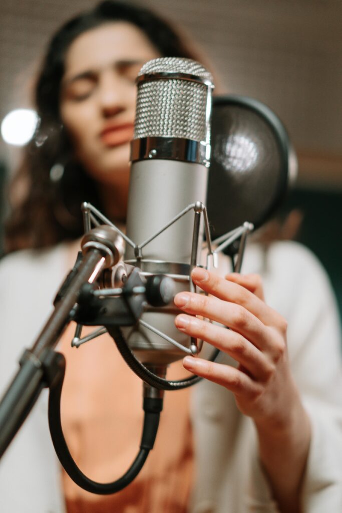 Women behind a microphone in a recording studio. Absolutely, you can learn to sing!