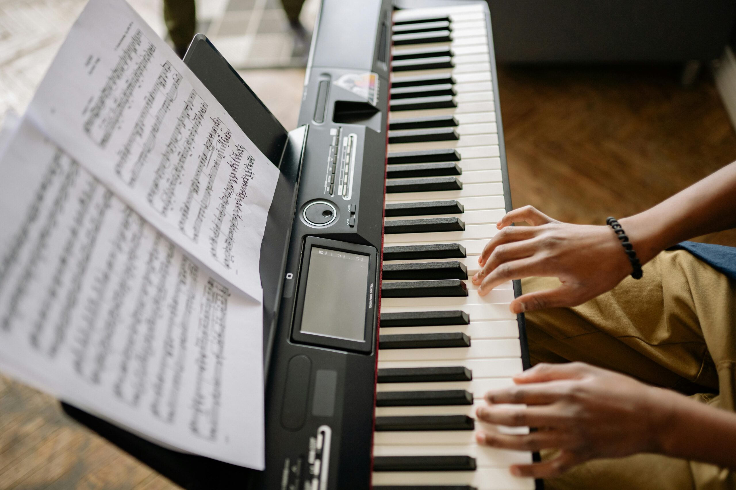 Learning to Sing or Play? A students hands of an electric piano practicing.