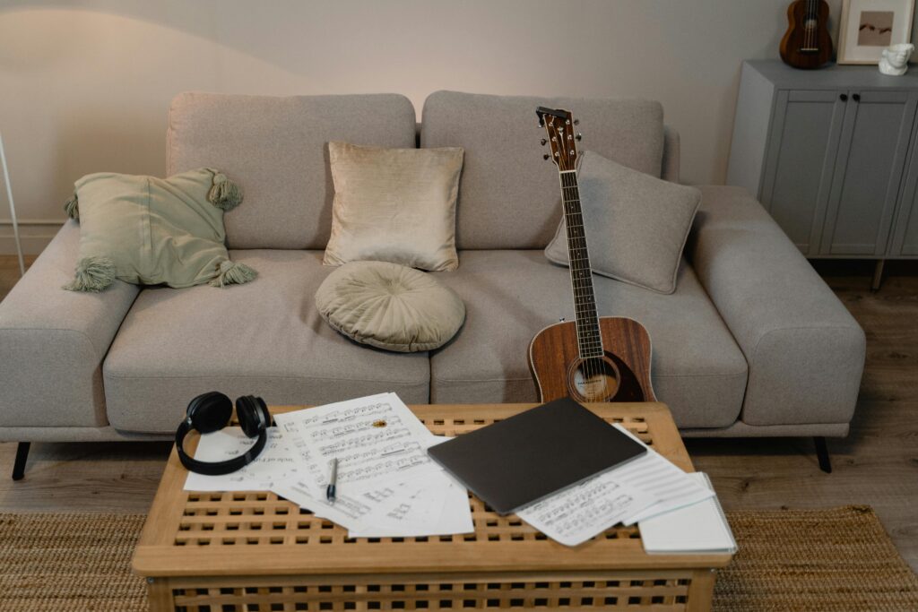 guitar, sheet music and head phones on a coffee table where a musician has been practicing.