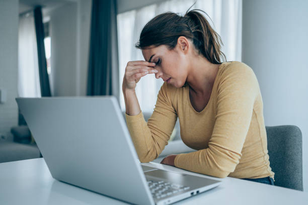 Women sitting with laptop holding her head stressed